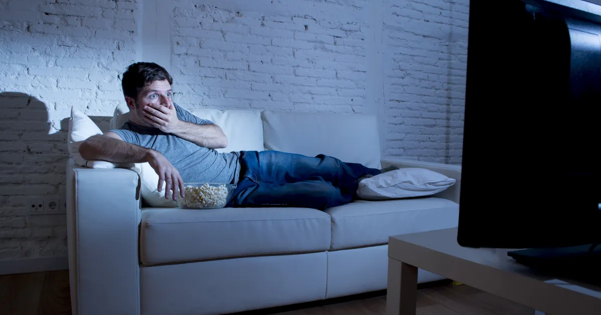 A man sitting on a couch watching a supply chain disaster movie.