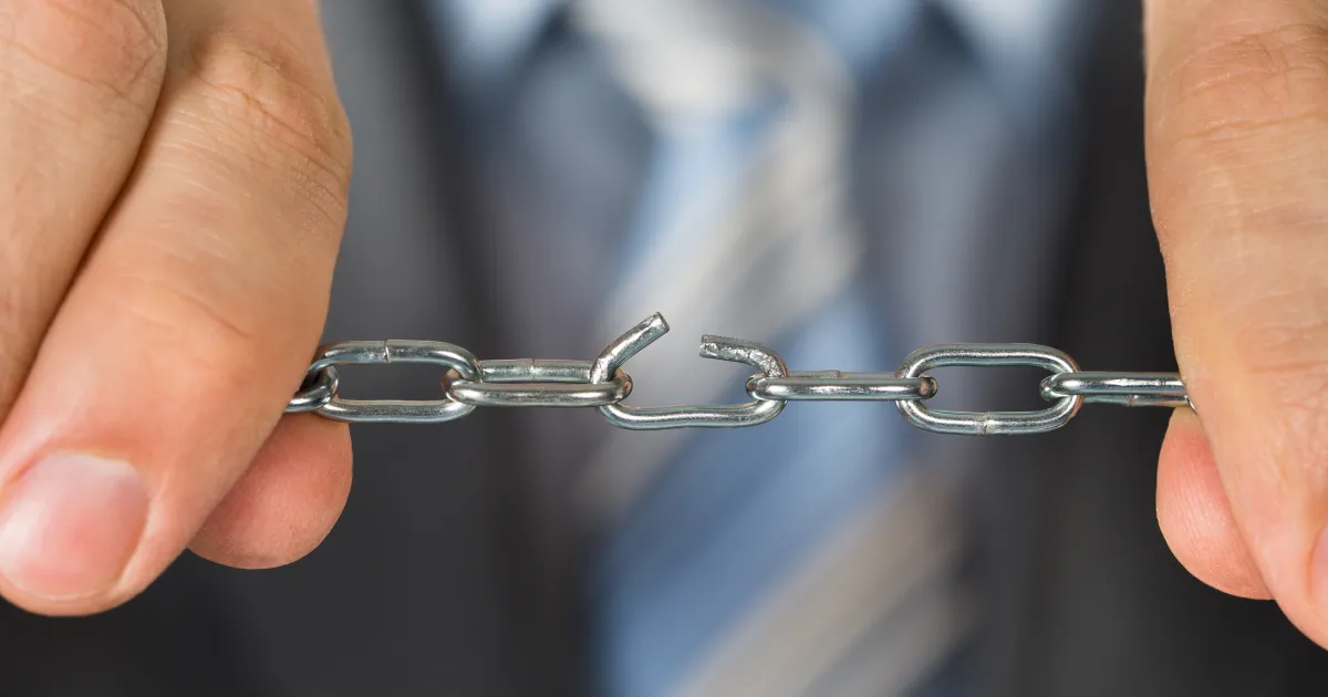 A man holding a chain with a weak link in the middle representing single and sole source dependencies in the supply chain.